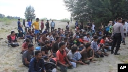 Sejumlah pengungsi Rohingya duduk di pantai selepas kapal yang mereka tumpangi berlabuh di Aceh Besar, pada 8 Januari 2023. (Foto: AP/Irwandi)