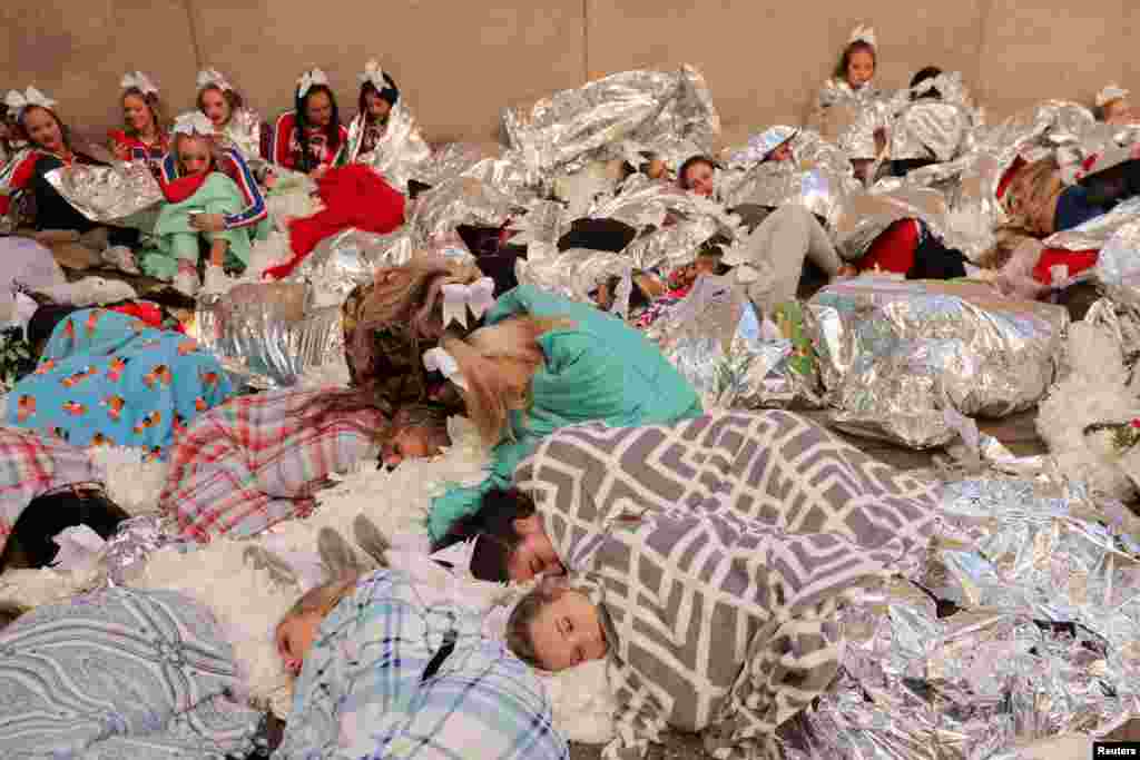 Los miembros de "Spirit of America" descansan debajo de las mantas para mantenerse calientes antes del 96º Desfile del Día de Acción de Gracias de Macy's en Manhattan, Nueva York, el 24 de noviembre de 2022.