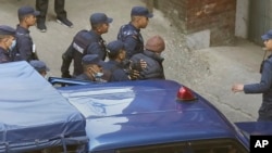 Nepalese police escort Charles Sobhraj, in brown cap, to the immigration office, in Kathmandu, Nepal, Dec. 23, 2022.