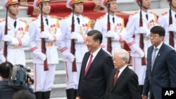 FILE - Presiden China Xi Jinping (kiri tengah), dan Sekretaris Jenderal Partai Komunis Vietnam Nguyen Phu Trong (kanan tengah), berjalan melewati penjaga kehormatan saat upacara penyambutan di istana presiden di Hanoi, Vietnam, 12 November 2017. (Hoang Dinh Nam /Pool Foto via AP)