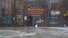 Two men walk through rushing water on Front Street, just a half block from the Bering Sea, in Nome, Alaska, Sept. 17, 2022. 