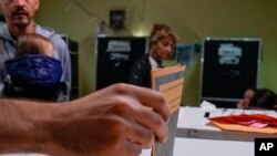 Eleitor descarrega o voto na urna, numa assembleia de voto em Roma, Itália, 25 de setembro. 
