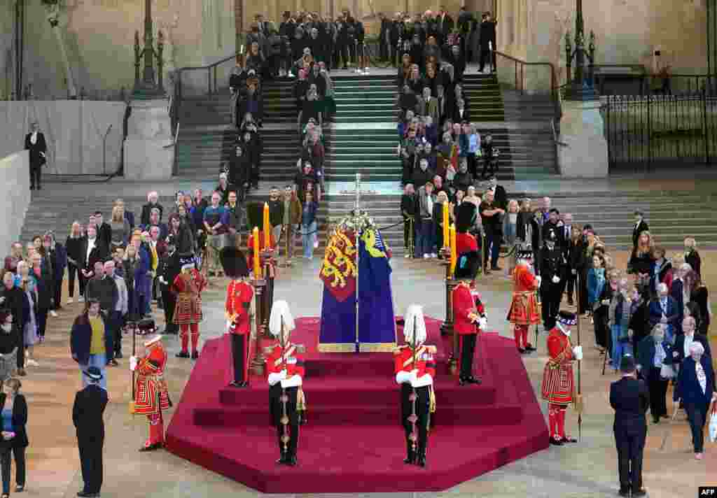 Members of the public file past the coffin of Queen Elizabeth II, draped in the Royal Standard with the Imperial State Crown and the Sovereign's orb and sceptre, lying in state on the catafalque in Westminster Hall, at the Palace of Westminster, London, ahead of her funeral on Monday.