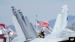 2022年9月23日，美国士兵在抵达韩国釜山港口的核动力航空母舰罗纳德·里根号的甲板上检查 F/A-18 超级大黄蜂战斗机。