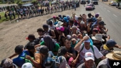 Para migran berkendara dengan truk, sementara migran lainnya mencari tumpangan di jalan yang menghubungkan Tapanatepec dengan Niltepec, Meksiko. Rombongan kafilah migran dari Amerika Tengah perlahan mengalir ke perbatasan AS, 29 Oktober 2018.