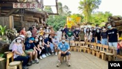 志記鎅木廠負責人王鴻權（藍襯衫者）與9月3日木工班參加者合照，他們將當日親手製作的小木櫈排成半圓形展示。（美國之音/湯惠芸）