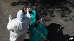 Seorang petugas kesehatan mengambil sampel swab seorang perempuan untuk tes COVID-19 di Hyderabad, India, 4 Februari 2022. (Foto: AP)