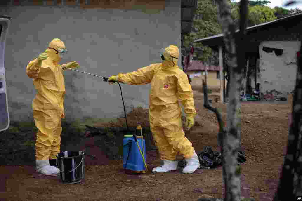 Gordon Kamara (left) is sprayed by Konah Deno after they loaded six patients suspected to have been infected by the Ebola virus into their ambulance in Freeman Reserve, Liberia, Sept. 30, 2014.