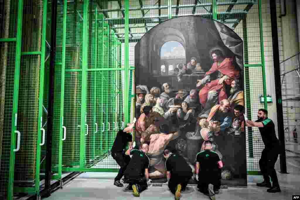 Workers carry a painting at the paintings' restoration site for the Notre Dame Cathedral on the outskirts of Paris, France, Sept. 6, 2022.