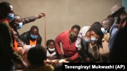 Des représentants de partis politiques surveillent de près un agent électoral qui présente un bulletin de vote au début du processus de dépouillement dans un bureau de vote à Lusaka, en Zambie, le jeudi 12 août 2021. 