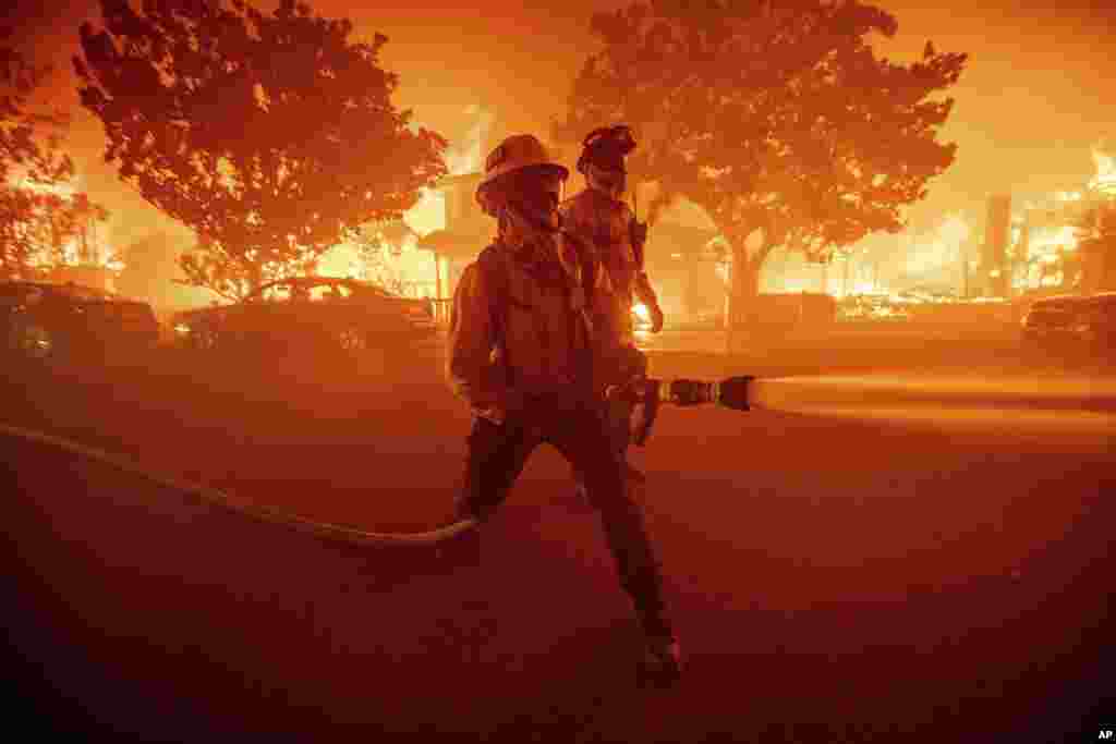 Os bombeiros combatem o incêndio de Palisades, enquanto este queima várias estruturas no bairro de Pacific Palisades, em Los Angeles, a 7 de janeiro de 2025.