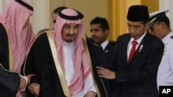 Indonesian President Joko Widodo, right, assists Saudi King Salman, center, to walk during their meeting at the presidential palace in Bogor, West Java, Indonesia, Wednesday, March 1, 2017.