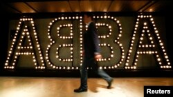 A man walks past the lit logo of the legendary Swedish pop group ABBA at the new "ABBA - The Museum" in Stockholm, May 6, 2013. 