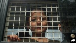 FILE - Ethnic Uighur Muslim boy stands inside a police van in Khlong Hoi Khong of southern Songkhla province, Thailand. He was in a group of 200 people rescued from a human trafficking camp.