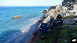 Firefighters retrieve the body of a migrant from the beach after a shipwreck on the island of Rhodes, southeastern Greece, Nov. 23, 2020.