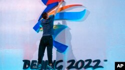 FILE - A crew member fixes a logo for the 2022 Beijing Winter Olympics before a launch ceremony to reveal the motto for the Winter Olympics and Paralympics in Beijing on Sept. 17, 2021. 
