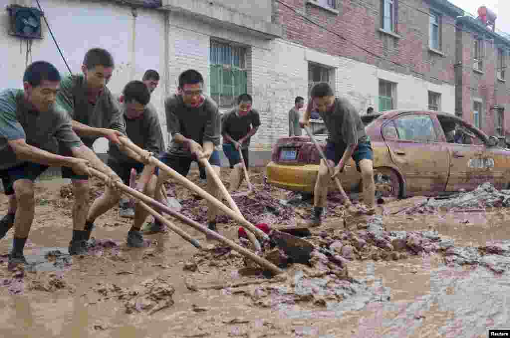 Chinese People's Liberation Army soldiers clear mud from a street in a flood-hit area in Hougoumen village of Fangshan district in Beijing, July 25, 2012.