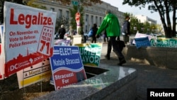 FILE - Pedestrians pass by a cannabis legalization campaign sign in Washington, Nov. 4, 2014.