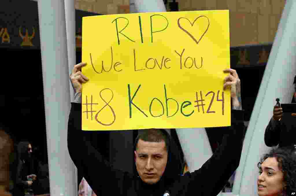 A man holds a sign memorializing Kobe Bryant at the LALive area across from Staples Center, home of the Los Angeles Lakers, after word of the Lakers star's death in a helicopter crash in downtown Los Angeles, Jan. 26, 2020.