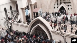 FILE - Relatives and onlookers gather outside a church after a bomb attack in the Nile Delta town of Tanta, Egypt, Sunday, April 9, 2017. 