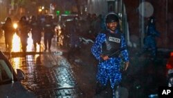 A Maldives policeman charges with baton towards protesters after the government declared a 15-day state of emergency in Male, Maldives, early Tuesday, Feb. 6, 2018. 