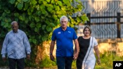 Cuba's President Miguel Diaz Canel walks with his wife Lis Cuesta Peraza before casting his vote at a polling station during the new Family Code referendum in Havana, Cuba, Sunday, Sept. 25, 2022. 