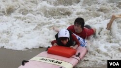 Austin Bramson takes a ride on a surfboard with the help of a Best Day at the Beach volunteer. (VOA/D. Grunebaum)