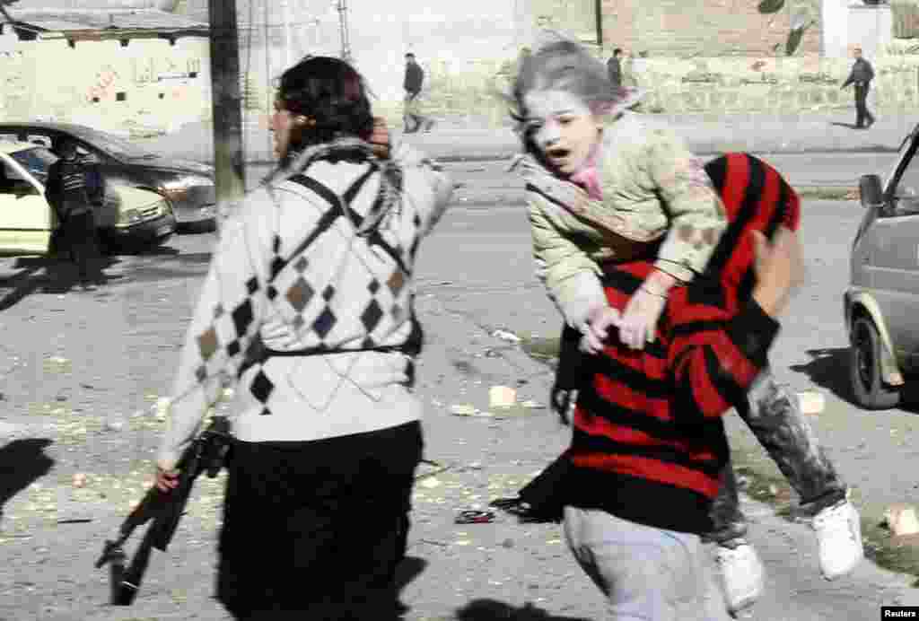A man carries a wounded girl who survived what activists say was an air strike by forces loyal to Syrian President Bashar al-Assad in Aleppo's al-Ansari al-Sharqi neighborhood.