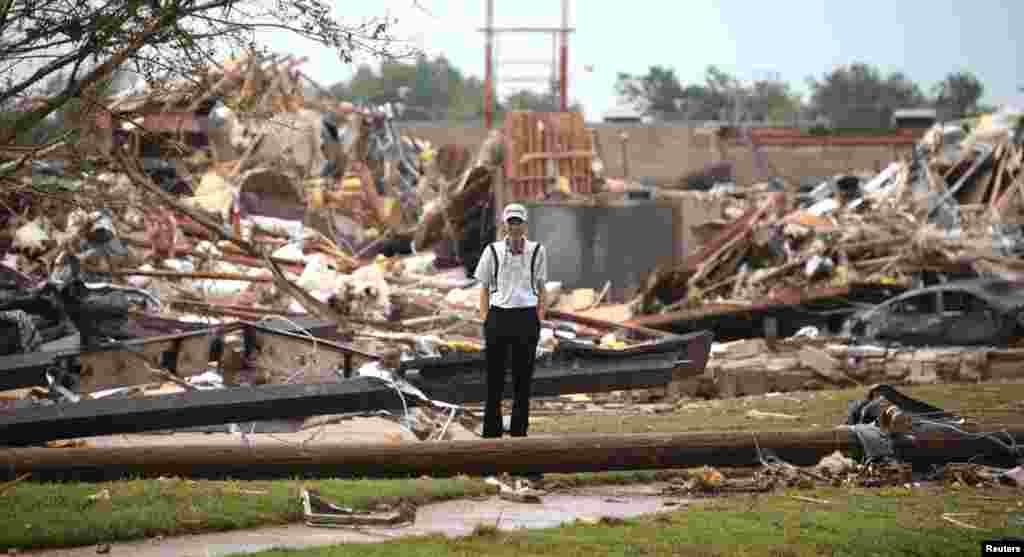 Seorang pria berdiri di tengah reruntuhan bangunan di Moore, negara bagian Oklahoma (20/5).