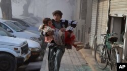 An injured boy carries an injured girl as he runs towards a safe area a few minutes after the suicide bombing in Quetta, Pakistan, Feb. 6, 2016. 