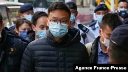 Stand News chief editor Patrick Lam is brought to the news outlet's office building in handcuffs after police were deployed to search the premises in Hong Kong's Kwun Tong district on Dec. 29, 2021. 