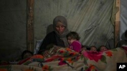資料照片：在加沙走廊汗尤尼斯的一處營地，瑞達·阿布·扎拉達(Reda Abu Zarada)用毯子蓋住自己和孩子，準備在帳篷中入睡。 (2024年12月19日)