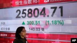 Seorang perempuan melewati papan informasi elektronik yang menunjukkan indeks gabungan di luar sebuah bank di Hong Kong, 31 Desember 2018.
