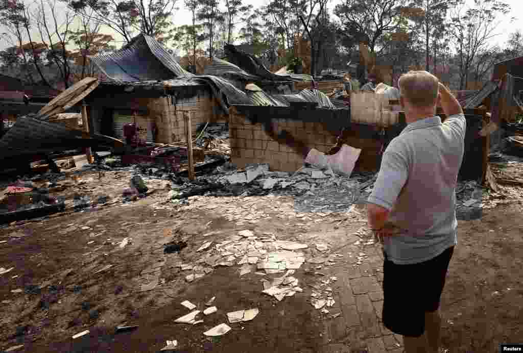 Colin Smith di depan rumah keluarganya yang hancur karena kebakaran di daerah pinggiran kota Blue Mountains di Winmalee, sebelah barat Sydney (21/10). (Reuters/David Gray)