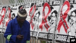 A man makes a call on a mobile phone as he passes past a World AIDS Day banners on the perimeter of an office building in Sandton, Johannesburg, South Africa, Dec. 1, 2014. (AP Photo/Denis Farrell) 