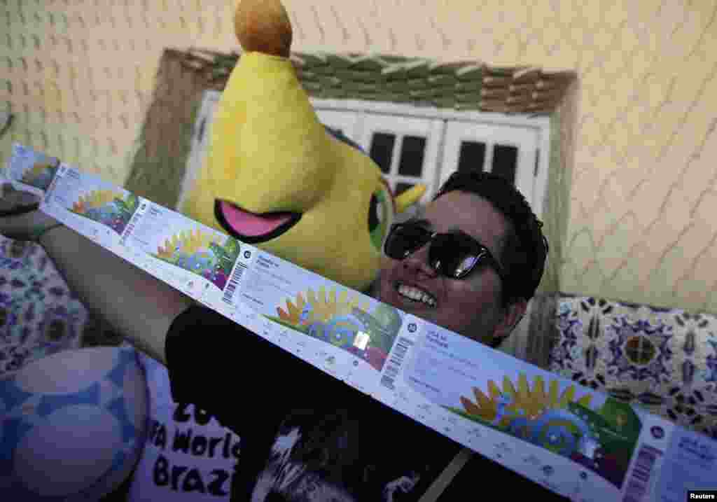 Um fã de futebol posa para a foto após comprar os seus bilhetes para o Mundial. Ao seu lado a mascote "Fuleco". Rio de Janeiro Abril 18, 2014. REUTERS/Rica