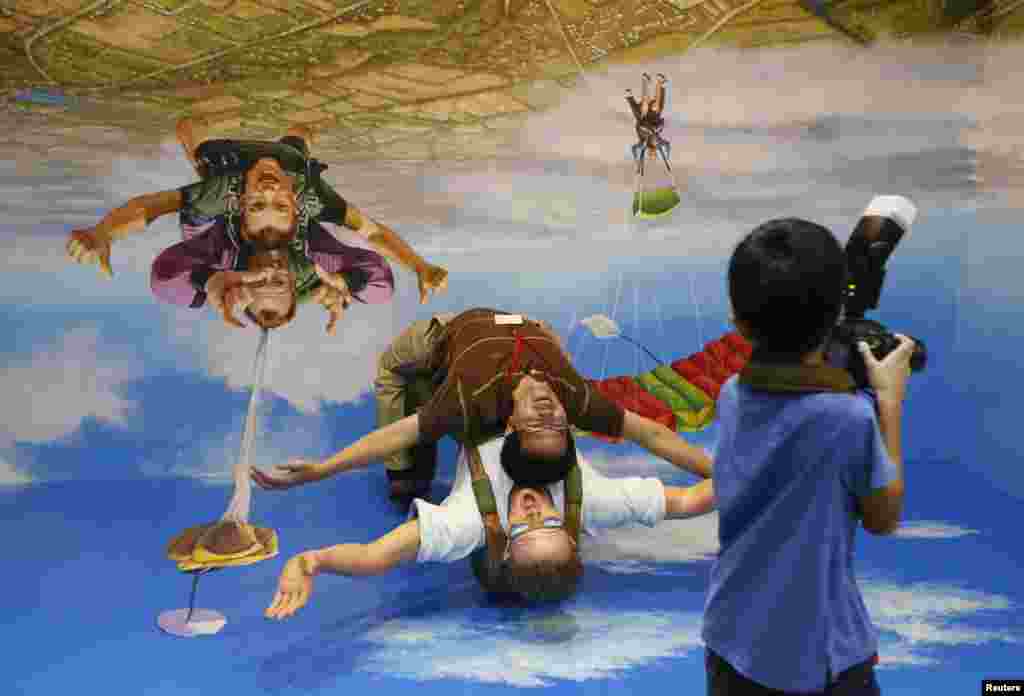 Seorang pengunjung di Taman Hiburan Sentosa di Singapura berpose di sebuah lukisan 3-Dimensi di sebuah museum 'Tipuan Mata'.