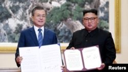 Presiden Korea Selatan Moon Jae-in dan Pemimpin Korea Selatan Kim Jong-un memperlihatkan "Deklarasi Pyongyang September" seusai penandatangan kesepakatan tersebut di Pyongyang, Korea Utara, 19 September 2018. (Foto; Pyeongyang Press Corps/Pool via REUTERS). 
