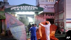 Workers at an embalming facility in Mexico City prepare to unload a truck containing dozens of the 145 bodies found in mass graves in northern Mexico, April 14, 2011