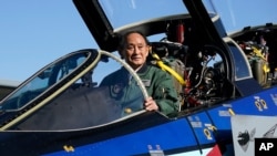 Japanese Prime Minister Yoshihide Suga sits on the cockpit of an F-4EJ Kai fighter jet of Japan's Air Self-Defense Force after reviewing troops at Iruma Air Base in Sayama, northwest of Tokyo, Nov. 28, 2020.