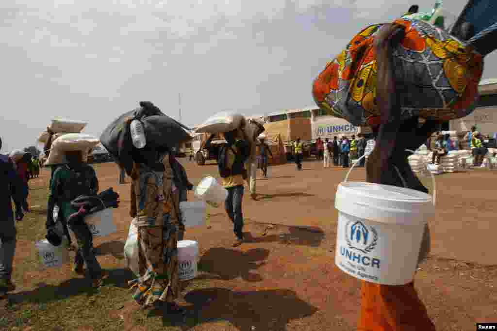 People displaced by the recent unrest collect food distributed by aid agencies at an IDP camp at the Mpoko international airport of Bangui, Feb. 12, 2014.