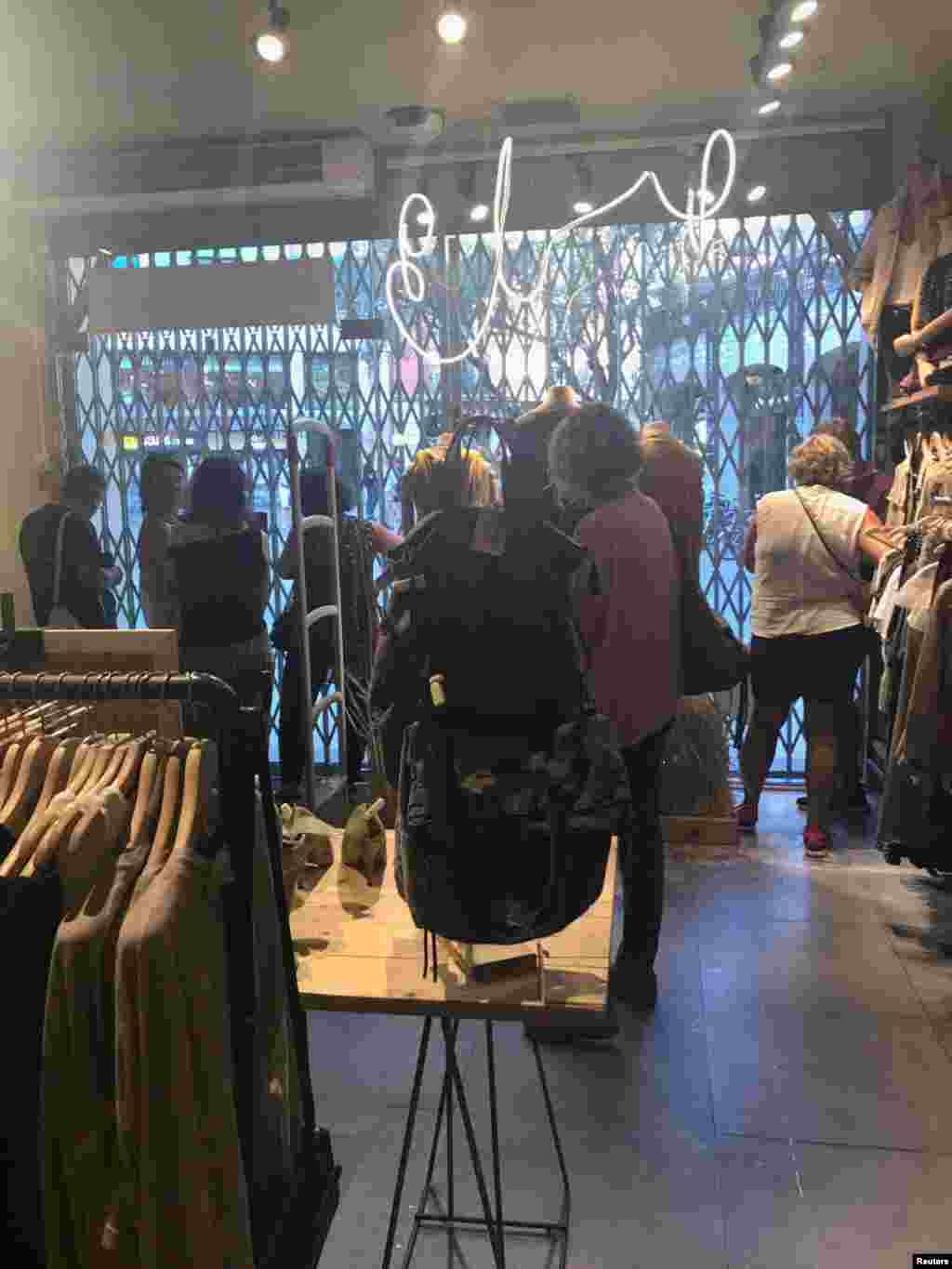 Personas se refugian en la tienda Systemaction, en Barcelona, España, que cerró sus puertas luego del ataque de una furgoneta a peatones en el histórico distrito de Las Ramblas.