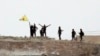 Fighters with the Kurdish People's Protection Units, or YPG, wave their yellow triangular flag on the outskirts of Tal Abyad, Syria, June 15, 2015.