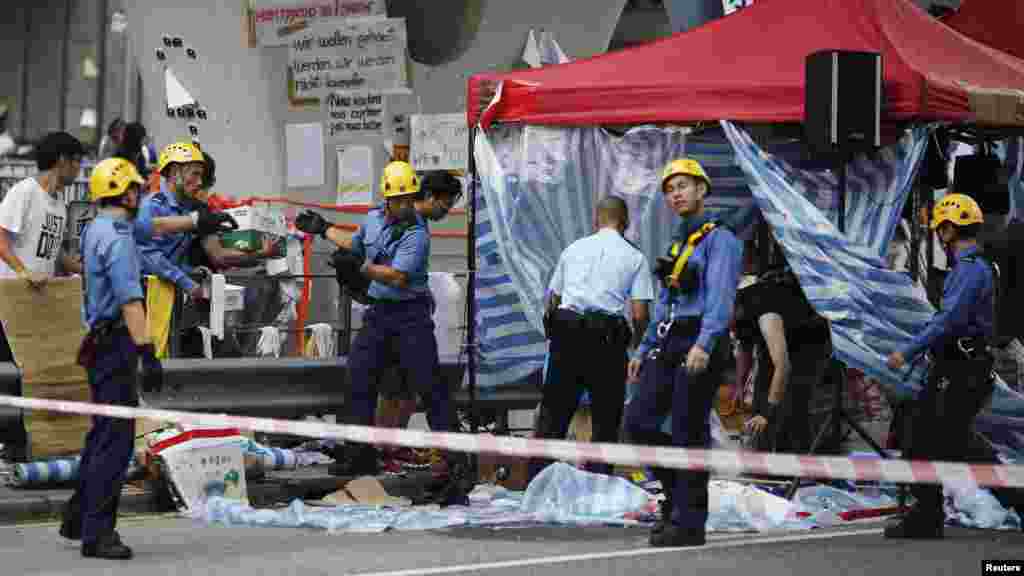 Firefighters remove a tent under a pedestrian bridge near the government headquarters in Hong Kong, Oct. 5, 2014.
