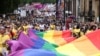 Para peserta pawai membentangkan bendera pelangi dalam pawai Pride 2022 di Kota London, Inggris, untuk memperingatai kesetaraan kaum LGBTQ+, Sabtu, 22 Juli 2022. (Foto: Henry Nicholls/Reuters)