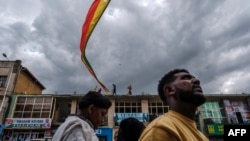 Les gens se tiennent sous une ancienne version du drapeau éthiopien dans la ville de Gondar, en Éthiopie, le 17 janvier 2022, alors que la ville se prépare à la célébration de Timkat.