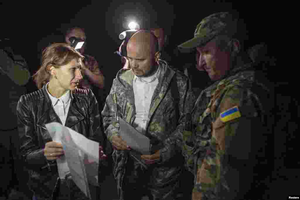 Representatives of the Ukrainian government forces (center and right), and of pro-Russian rebels (left) talk before exchanging prisoners-of-war (POWs), north of Donetsk, eastern Ukraine, Sept. 12, 2014. 