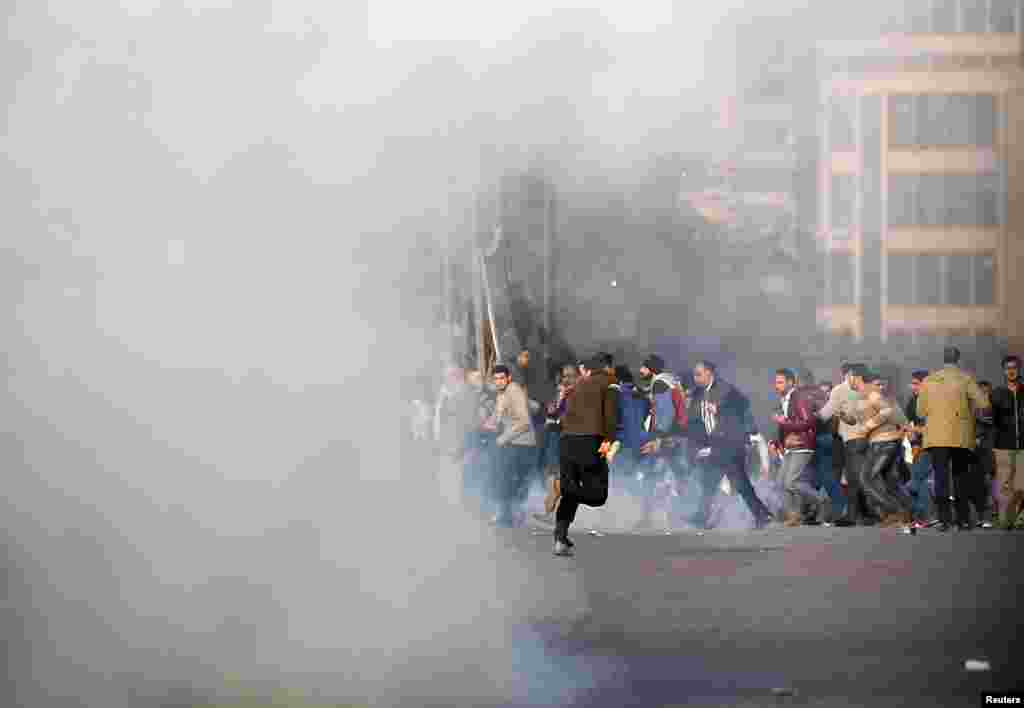 Anti-government protesters and members of the Muslim Brotherhood flee after tear gas was fired by riot police during clashes on Ramsis Street, near Tahrir Square, Cairo, Jan. 25, 2014.