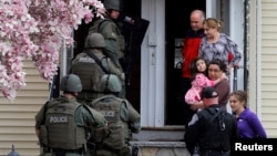 Polisi khusus melakukan pemeriksaan dari rumah ke rumah untuk mencari tersangka Dzhokar Tsarnaev di kota Watertown, Massachusetts, sementara warga diminta keluar rumah mereka (19/4). 