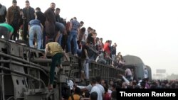 People gather at the site where train carriages derailed in Qalioubia province, north of Cairo, Egypt, April 18, 2021.